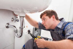 A homeowner checks a water meter beside a basement pipe while a utility bill rests nearby.